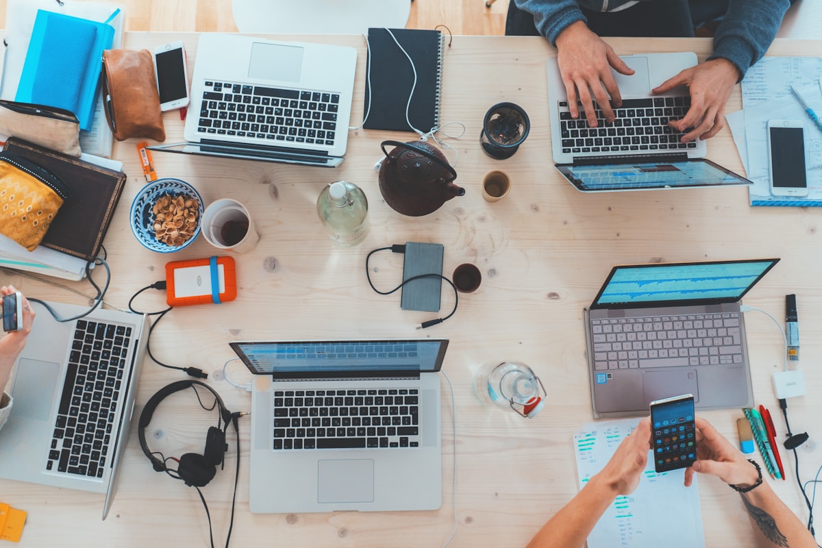 Schreibtisch von oben mit Notebooks, Unterlagen und Notizbüchern (KI-generiert)